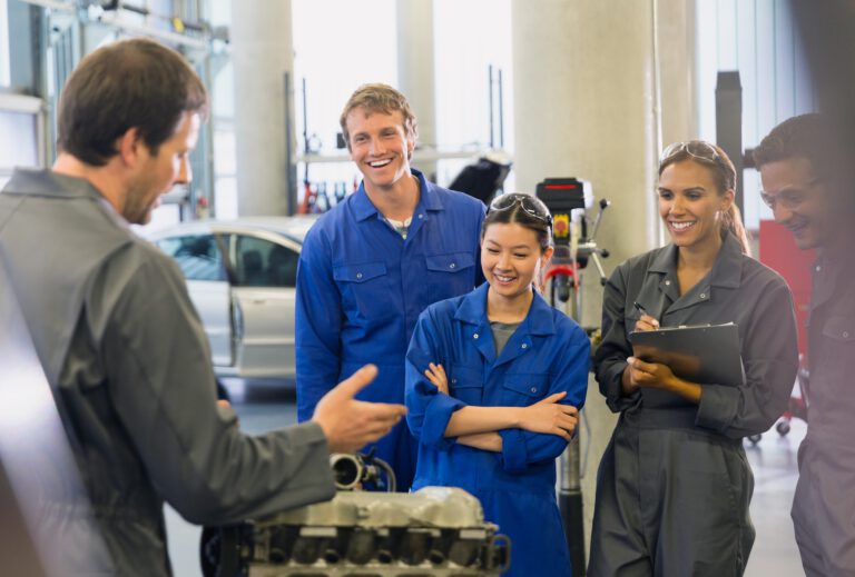Automotive technicians discussing in a workshop with a recruiter.
